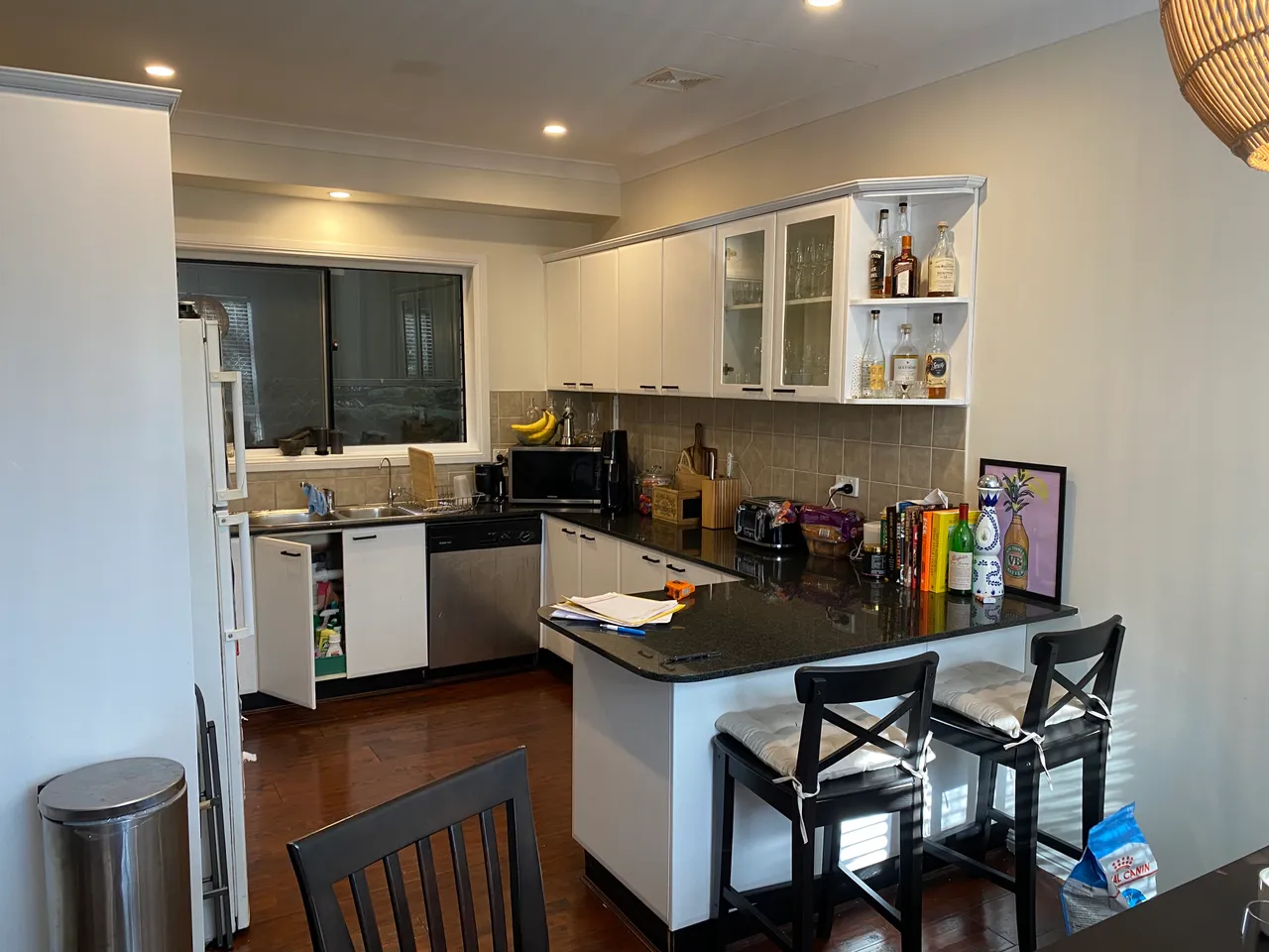 A kitchen with white doors, a black granite benchtop and beige tiles, before